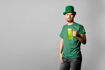 Happy St. Patrick's Day. A red-haired guy in a green hat raises his hands up, a glass of green beer