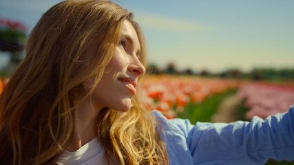 Beautiful girl making selfie in flower field. Young woman looking at camera.