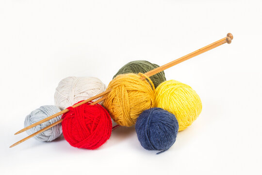 Coloridos ovillos de lana y agujas de madera sobre un fondo blanco liso y aislado. Vista de frente y de cerca. Copy space