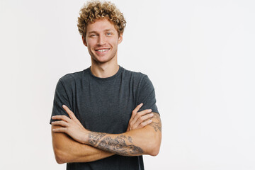Young blonde man with curly hair smiling and looking at camera - obrazy, fototapety, plakaty