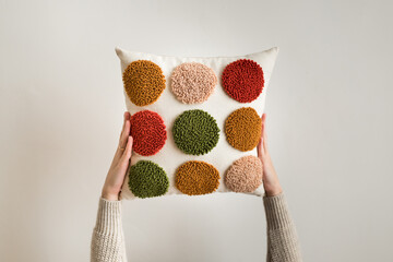 Punch needle embroidery pillow diy. Close-up of woman hands holding pillow. Product is made...
