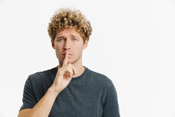 Young blonde man frowning while making winner gesture