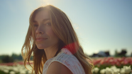 Romantic woman looking with love in flower park. Calm girl smiling in sunrise.
