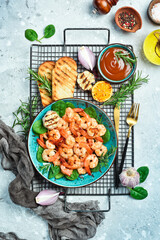 Grilled shrimp served with lemon and sauce. Seafood on a plate. On a gray stone background. Top view.