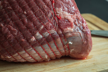 raw roast beef meat on wooden cutting board closeup