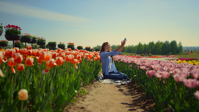 Bright tulip field and young woman making selfie in flower background