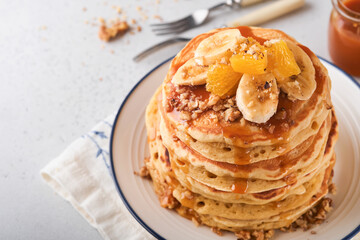 Pancakes. Homemade fluffy pancake with banana, walnut and caramel for breakfast on light concrete background. Delicious pancakes for traditional American breakfast. Selective focus. Mock up.