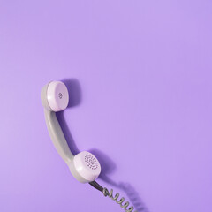 Retro style visual with phone receiver on pastel purple background. Minimal flat lay. Communication...