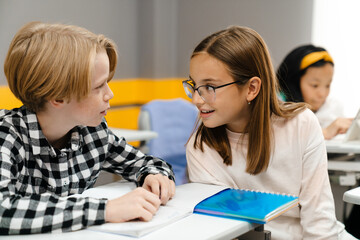 White pupils talking and smiling together during class © Drobot Dean