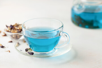 Thai blue Anchan tea in a glass cup and teapot on a wooden background.