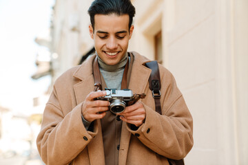 Middle eastern man taking photo on retro camera at city street