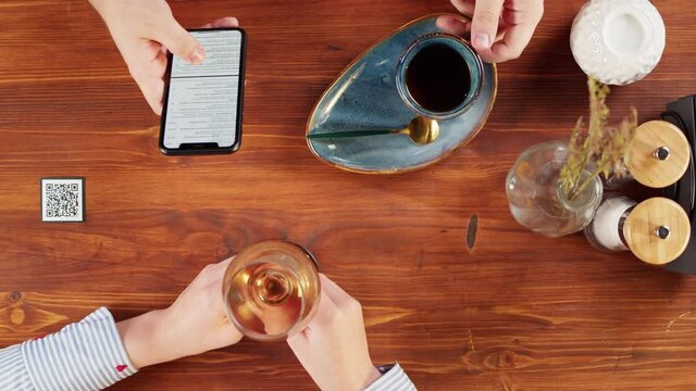 Man using online menu in cafe top view, scanning qr code with smartphone in restaurant . Modern technology, ordering meal in application. Contactless touch-free payment in app.