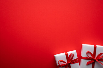 Creative Valentines Day postcard design with white gift box and red ribbon bow on red paper...