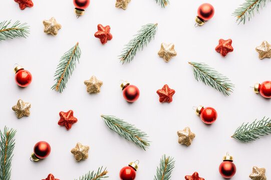 Creative Christmas background with Christmas balls, pine twigs, red and golden stars decorations on white background. Flat lay, top view, copy space