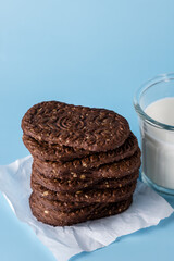 Stack of Delicious Chocolate Cookies with Oatmeal and Glass of Milk on Blue Background Copy Space Tasty Homemade Cookies
