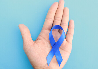 Blue Ribbon Symbol - Prostate Cancer Problems one hand crossed on a blue background