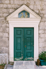 Fototapeta na wymiar Green wooden door on the stone facade of the temple