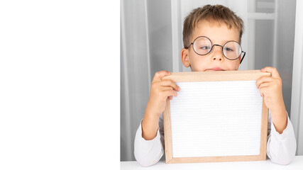 Banner of Funny adorable little boy in glasses with letter board. Education. 1 September. Back or First to school. Copy space