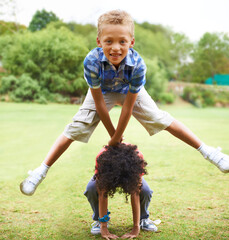 Leapfrogging. A young boy doing a leapfrog over his friend's back.