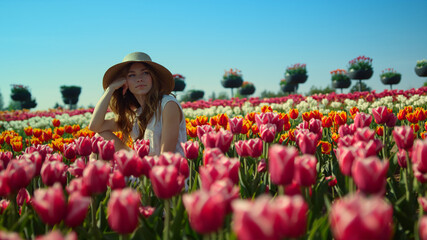 Relaxed woman sitting in beautiful spring garden. View of blooming tulip field. 