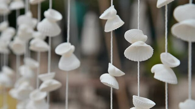Moving of Seashells mobile hanging with light wind blowing on the beach. Beautiful handicrafts produced by sea shell
