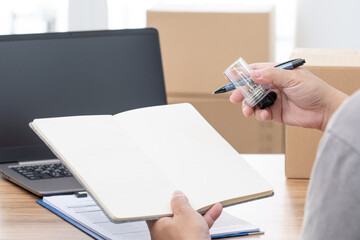 Fototapeta premium Close up hand a man hold car headlight bulb halogen and bulb case and hold note book with laptop on wood table in car service office : car part check and service concept