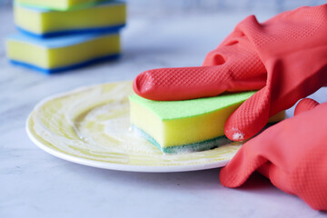 sponge , rubber gloves and colorful plate on blue 