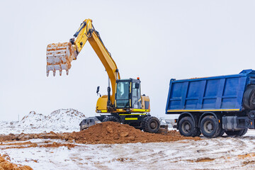 Powerful excavator digs a foundation pit for the construction of a residential building. Loading earth into a dump truck. construction production. Excavation. Close-up.