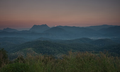 Obraz premium Mountain ridge, mountain range and village with faint fog in an evening