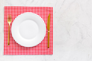White plate with fork and knife on table napkin. Table setting