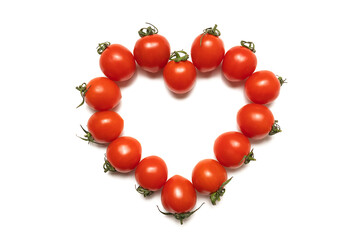 Small cherry tomatoes arranged in a heart shape isolated on a white background. Heart of red tomatoes. Top view isolated. Happy Valentine's day concept. Copy space. Close-up.