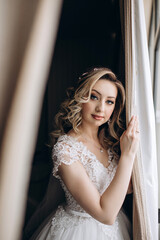 Fototapeta premium Bride in a white dress at the window. Bride morning. Getting ready for the upcoming wedding.