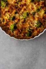 Homemade baked pot pie with Romanesco cabbage, chicken breast and cheese in a round ceramic baking dish on a gray background, top view