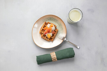 Vegan, gluten free waffles with pudding and oranges served with green milk, napkin on neutral background. Healthy meal, tasty homemade breakfast.