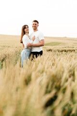 Naklejka na ściany i meble a couple in love stands among a wheat field and hold hands. a guy and a girl are walking in nature. vacation outside the city