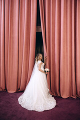 The bride in a white dress holds a beautiful wedding bouquet. Significant day. Burgundy background.