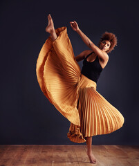 Dedication to expression. Female contemporary dancer in a dramatic pose against dark background.