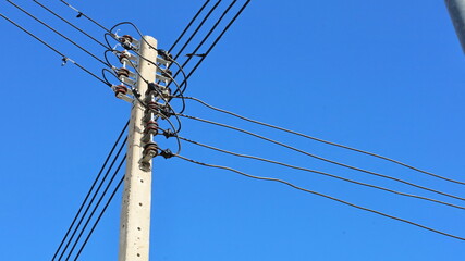 Electrical wires on concrete poles. Low voltage transmission line on concrete pole on bright blue...