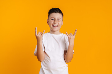 Brunette white boy in t-shirt smiling and making horn gesture