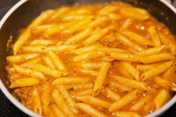 penne pasta with bolognese sauce in a pan
