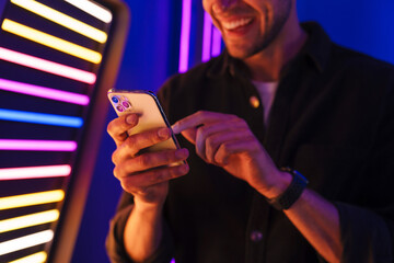 Young bristle man laughing while using mobile phone