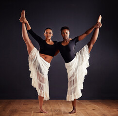 Sisters in symmetry. Two young female contemporary dancers using a soft white white skirt for...