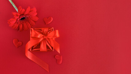 gift box with ribbon, gerbera flower, heart on red background.  valentines day concept. greeting card. copy space, place for text, banner