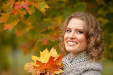 Naklejka na ściany i meble Portrait of beautiful young woman holding autumn leaves