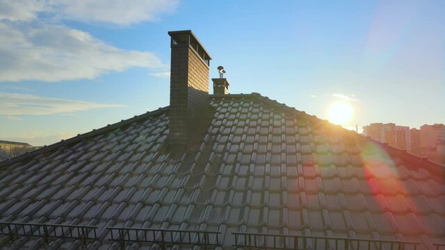 Closeup snow guard for safety in winter on house roof top covered with ceramic shingles. Tiled covering of building