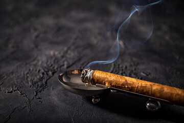 Premium cigar placed in ashtray on black background