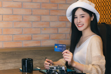 Obraz na płótnie Canvas Young asian girl holding credit card and using credit card for shopping or booking online of airline ticket or hotel Happy Traveler woman sitting at cafe with smile Vacation Travel and Holiday concept