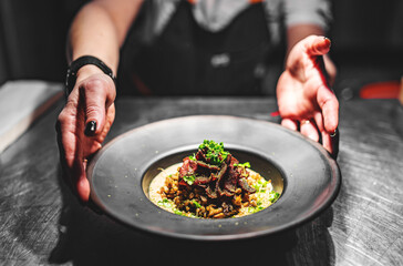 chef hand holding plate with Spelt with meat