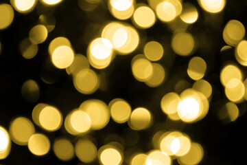 Defocused bokeh christmas big gold lights on black background. Blurred abstract gold glitter texture. Gold bokeh glitter wallpaper for Christmas, New year or festival, holiday background.
