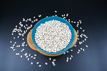 Small white beans on the green plate and wooden board. Copy space top view